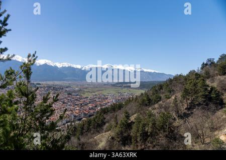 Vista panoramica della valle di Razlog, che mostra la città di Razlog e le montagne innevate di Pirin sullo sfondo, durante una soleggiata giornata primaverile Foto Stock