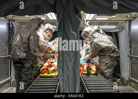 La decontaminazione delle persone ferite dopo un presunto incidente che coinvolge sostanze pericolose, i vigili del fuoco e le organizzazioni umanitarie esercitano la creazione di un Foto Stock