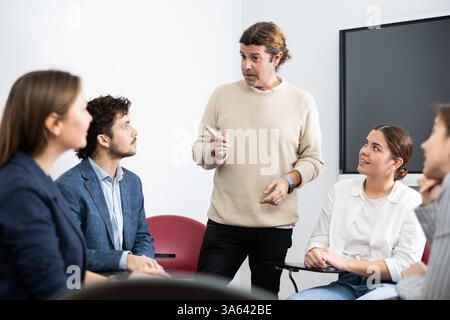 Professore esperto che spiega il soggetto ad aula piena di studenti Foto Stock