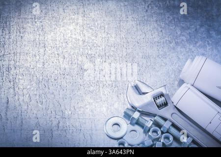 Bullone chiave regolabile, rondelle, dadi, bulloni e disegni di costruzione arrotolati su sfondo metallico, concetto di manutenzione della vista orizzontale Foto Stock