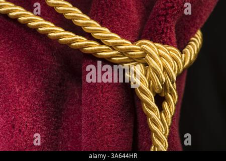 Rosso tenda in velluto con fiocco. Chiudere il nodo sulla corda Foto Stock