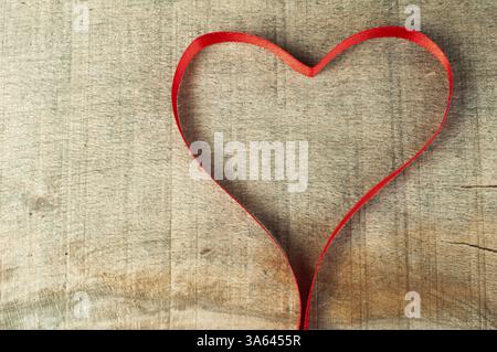 â a cuore di â€‹€‹di burocrazia. Cuore di nastro rosso su sfondo di legno Foto Stock