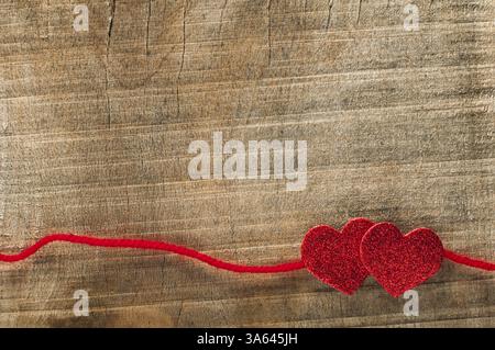 Nastro rosso e cuori su fondo in legno Foto Stock