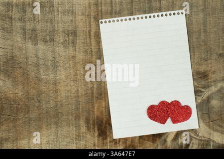 Cuori rossi e il foglio di carta bianco su sfondo di legno Foto Stock
