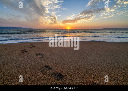 Impronte nella sabbia che conduce verso l'Ocean Sunrise Foto Stock