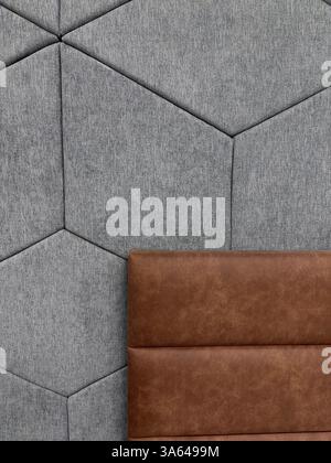 Una sezione di interni moderni, caratterizzata da una parete con tessuto grigio chiaro disposto in un motivo esagonale e un cuscino in pelle marrone scuro, che fornisce uno sfondo visivamente attraente per varie applicazioni commerciali concetto di interior design, arredamento e ospitalità. Foto di alta qualità Foto Stock