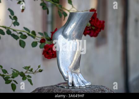 Piede di una donna in punta di piedi, scultura color argento, metallo lucido, rose rosse sullo sfondo, Steinbach, Michelstadt, Odenwald, Assia, Germania, E. Foto Stock