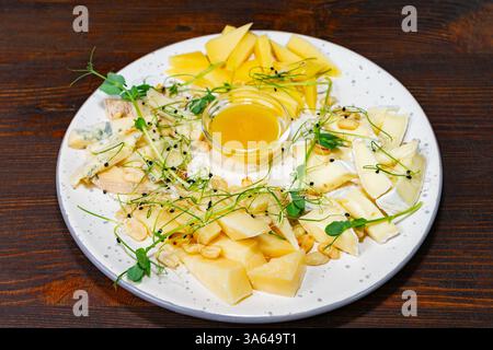 Un piatto ben organizzato con vari formaggi, frutta fresca e miele. Il piatto è servito in un ristorante elegante, perfetto per la condivisione o la condivisione Foto Stock