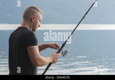 Uomo con gancio di pesce di fronte alla diga di montagna. Bulgaria Foto Stock