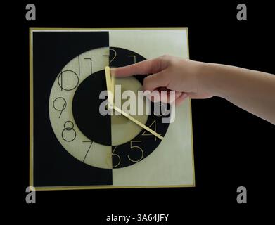 Mano di clock essendo spinto indietro. Isolato su nero Foto Stock