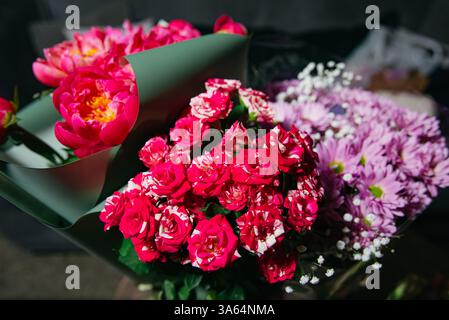 Vivace collezione di bouquet floreali con rose a righe, peonie, crisantemi e respiro del bambino in involucri decorativi. Foto Stock