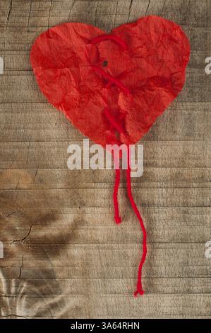â â di carta rossa arricciata su tavola di legno Foto Stock