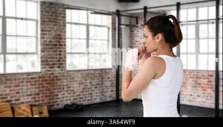 Donna in palestra che pratica il pugilato, concentrandosi sulla tecnica e sulla forza Foto Stock