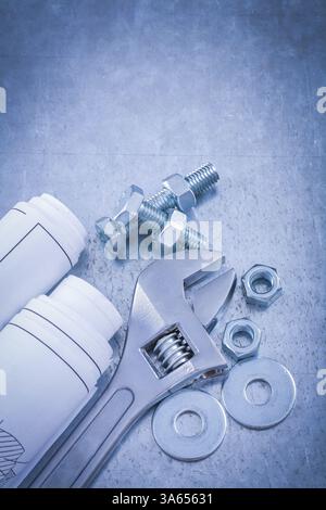Bulloni chiave regolabili, rondelle, dadi, bulloni e disegni di costruzione arrotolati su sfondo metallico, concetto di manutenzione dello spazio di copia Foto Stock