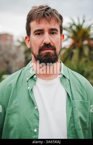 Ritratto verticale di un giovane con la barba che guarda direttamente la fotocamera, trasuda sicurezza e forza. La sua intensa espressione cattura lo spettatore, rivelando livelli di personalità e profondità. Foto di alta qualità Foto Stock