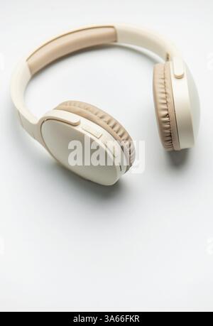 Cuffie wireless beige e bianche isolate su sfondo bianco, che rappresentano l'ascolto di musica, il piacere del podcast o la comunicazione audio Foto Stock