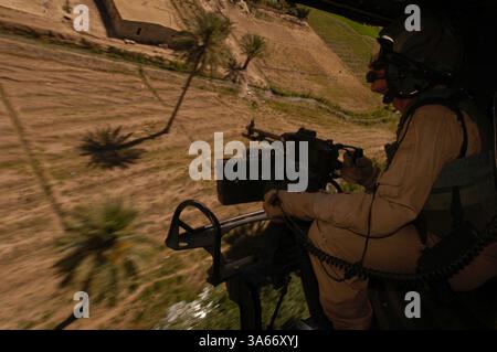 25 maggio 2004; Camp Taqaddum, Iraq; arroccato dietro una mitragliatrice in un elicottero UH-1N Huey, staff Sgt. MARK J. COVILL, 29, un capo equipaggio con Marine Light Attack Helicopter Squadron 775, esplora l'area intorno a una fattoria vicino a Camp Taqaddum, Iraq, durante una pattuglia di ricognizione il 25 maggio 2004. I Marines di HMLA-775, uno squadrone di riserva con base a Camp Pendleton, California, e Johnstown, Pa., forniscono sicurezza ai convogli del 1st Force Service Support Group che trasferiscono rifornimenti in tutta la provincia di al Anbar in Iraq. I piloti utilizzano la vista dall'alto e la potenza di fuoco per cercare di individuare ed eliminare possibili expl lungo la strada Foto Stock