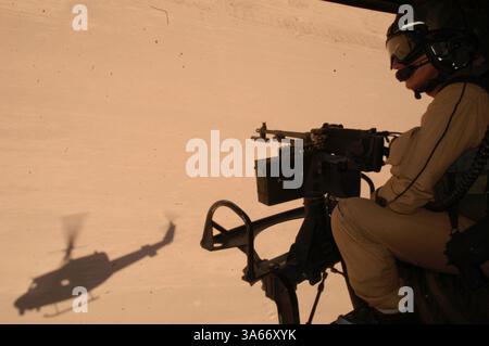 25 maggio 2004; Camp Taqaddum, Iraq; arroccato dietro una mitragliatrice in un elicottero UH-1N Huey, staff Sgt. MARK J. COVILL, 29, un capo equipaggio con Marine Light Attack Helicopter Squadron 775, esplora l'area intorno a una fattoria vicino a Camp Taqaddum, Iraq, durante una pattuglia di ricognizione il 25 maggio 2004. I Marines di HMLA-775, uno squadrone di riserva con base a Camp Pendleton, California, e Johnstown, Pa., forniscono sicurezza ai convogli del 1st Force Service Support Group che trasferiscono rifornimenti in tutta la provincia di al Anbar in Iraq. I piloti utilizzano la vista dall'alto e la potenza di fuoco per cercare di individuare ed eliminare possibili expl lungo la strada Foto Stock