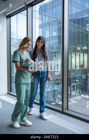 Medico donna in clinica ospedaliera che indossa uniforme medica revisione documenti con paziente Foto Stock