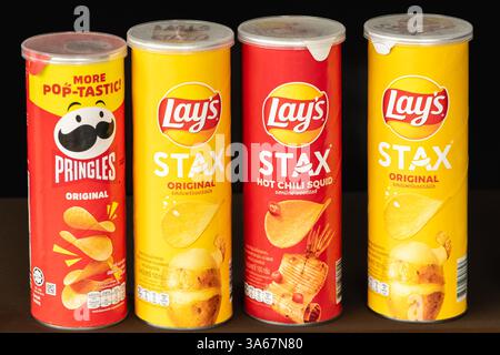 Lattine colorate di Pringles e patatine Stax di Lay su uno scaffale del supermercato, che offrono un'ampia varietà di sapori. Foto Stock