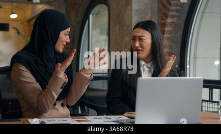 Due donne donne multirazziali donne d'affari intern boss donne d'affari asiatiche donna araba musulmana imprenditrice in hijab parlare lavorare analizzare dati laptop Foto Stock