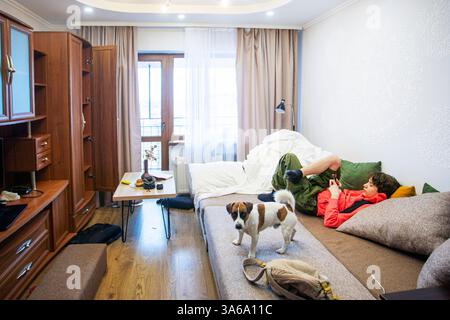 ragazzo che gioca una partita accanto a jack russell terrier sul divano della stanza Foto Stock