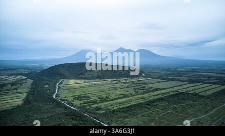 Una vista aerea mozzafiato che mostra un vasto paesaggio verdeggiante annidato tra maestose montagne Foto Stock