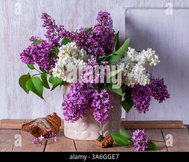 Bouquet di lillate multicolore, trucioli di legno e insetti su sfondo chiaro. Primavera natura morta di un bouquet di lills su un tavolo di legno, stile rustico Foto Stock