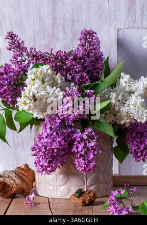 Bouquet di lillate multicolore, trucioli di legno e insetti su sfondo chiaro. Primavera natura morta di un bouquet di lills su un tavolo di legno, stile rustico Foto Stock