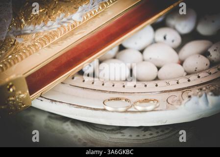 Vassoio d'argento sul tavolo delle nozze pieno di caramelle, bibbia e ghirlande durante una cerimonia di nozze greco-ortodossa Foto Stock