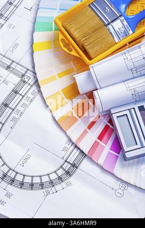 Disegni arrotolati e pennelli nella calcolatrice dei vassoi sulla tavolozza dei colori Foto Stock