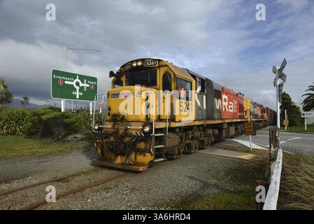 HOKITIKA, NUOVA ZELANDA, 29 AGOSTO 2020: Un treno merci attraversa la strada principale di Hokitika vicino alla rotatoria sulla State Highway 6 Foto Stock