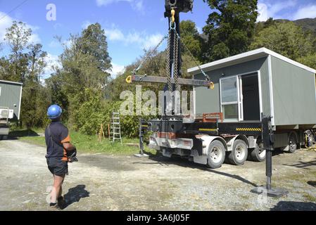 GREYMOUTH, NUOVA ZELANDA, 21 OTTOBRE 2020: Un operatore di gru lavora per sollevare un piccolo edificio da un camion sui suoi pali Foto Stock