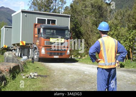 GREYMOUTH, NUOVA ZELANDA, 21 OTTOBRE 2020: Un lavoratore di costruzione attende l'arrivo di un operatore di gru che solleverà un piccolo edificio da un camion ont Foto Stock