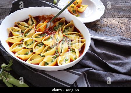 Conchiglie ripiene con piselli e formaggio in salsa di pomodoro Foto Stock