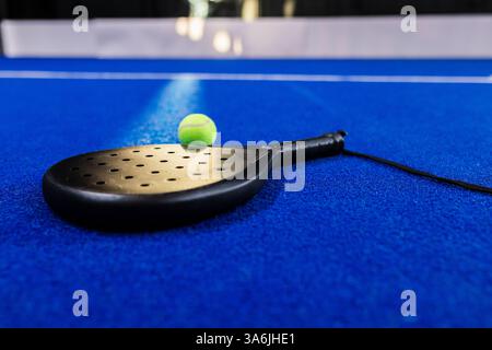 Racchetta Padel e palla da tennis sul campo blu, pronti all'azione Foto Stock