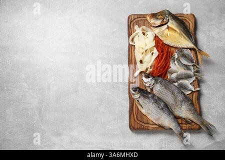 Molti diversi spuntini di pesce secco sul tavolo grigio chiaro, vista dall'alto. Spazio per il testo Foto Stock