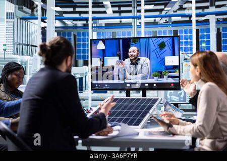 I ricercatori di fabbrica parlano di nuovi materiali fotovoltaici in videocall online. Uomini d'affari nell'impianto di produzione di pannelli solari discutono dei prototipi di recente sviluppo durante una riunione di teleconferenza Foto Stock