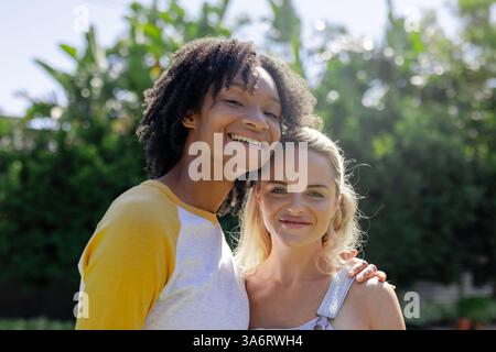 Le amiche sorridenti si godono una giornata di sole insieme a bordo piscina Foto Stock
