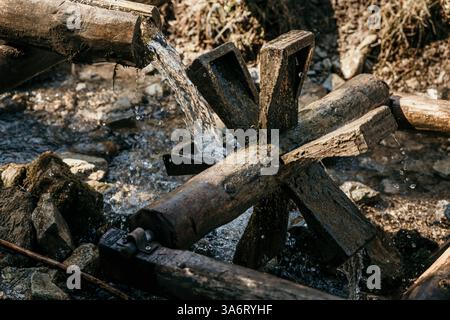 Ruota ad acqua in legno che gira in un ruscello, foto orizzontale Foto Stock