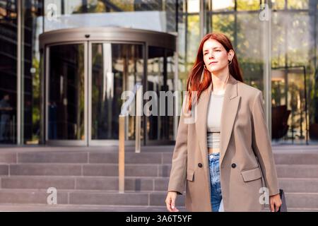 donna d'affari che cammina di fronte all'edificio dell'ufficio Foto Stock