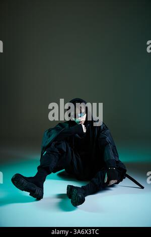 L'uomo elegante con un abbigliamento scuro si mette in posa in un ambiente elegante. Foto Stock