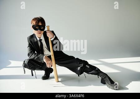 L'uomo vestito con stile si fa notare con un pipistrello, dando prova del suo senso della moda. Foto Stock
