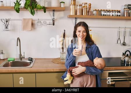Una madre amorevole condivide un momento tenero con il suo bambino in una cucina calda e invitante. Foto Stock