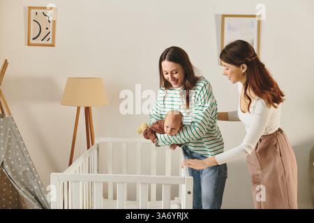 Due madri amorevoli adorano un momento di tenerezza con il proprio bambino in un accogliente salotto. Foto Stock