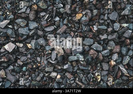 Piccole rocce grigie con finitura a terra. sfondo nero in pietra. Foto Stock