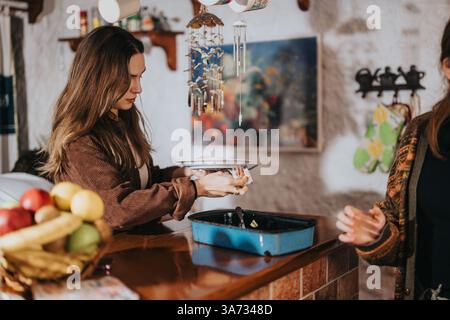 Giovane donna che pulisce i piatti in un ambiente interno rustico e accogliente Foto Stock