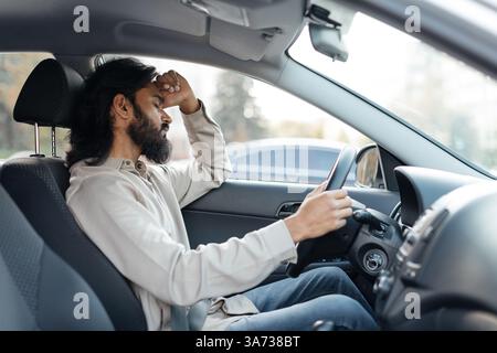 Uomo indiano in auto che mostra frustrazione o stanchezza, occhi chiusi, Foto Stock