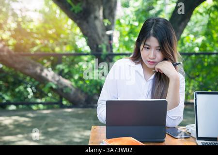 Giovane donna d'affari seduta a un tavolo con un computer portatile nel caffè. Blogging freelance al lavoro. Donna che usa un notebook. Foto Stock