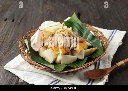 Kupat Tahu, popolare menu per la colazione da Giava Occidentale, Indonesia. Torta di riso compressa servita con tofu giallo, scout, salsa di arachidi piccanti e Kerupuk Foto Stock